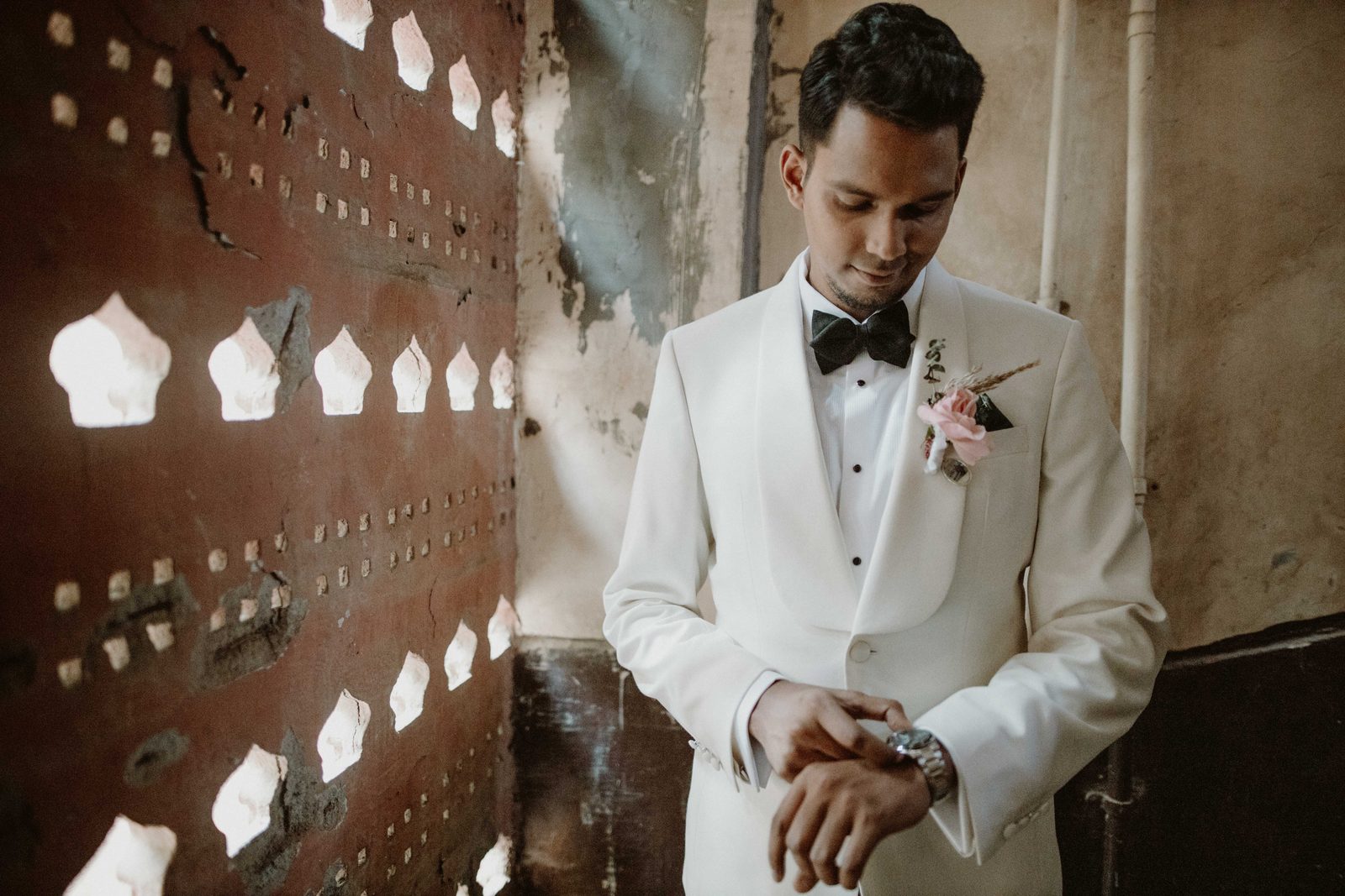 Groom in a white tuxedo with his boutonnière